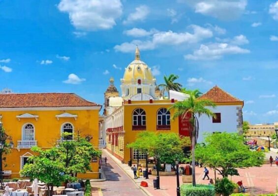 Vista panorámica de Cartagena con edificios coloniales coloridos y una cúpula amarilla destacando bajo un cielo azul, perfecta para un city tour.