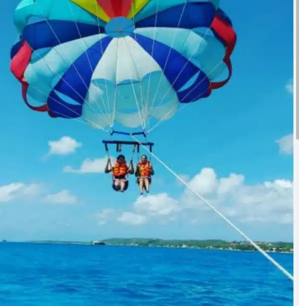 una pareja volando sobre el mar de san andres, practicando la actividad del parasail.